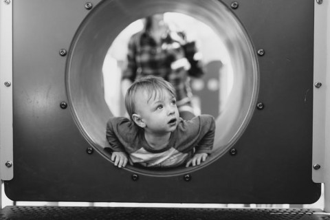 young boy in playground pipe