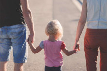young child holding hands with an adult on each side