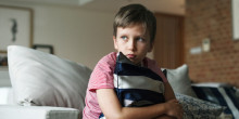 boy sitting on bed clutching a pillow - looking scared
