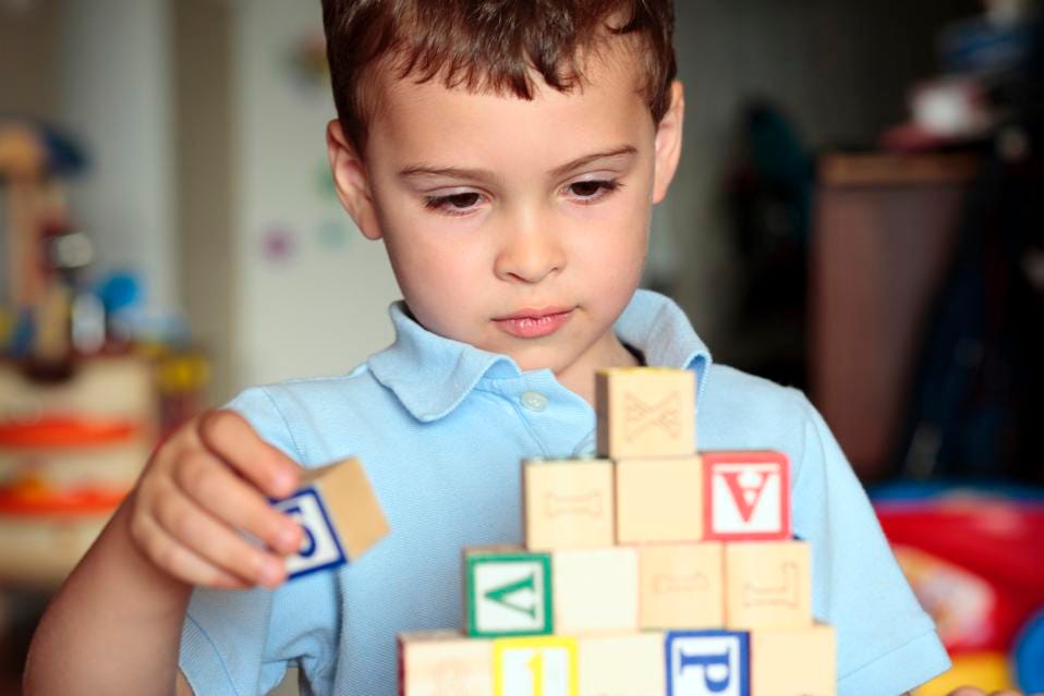 Child with autism deciding where is the best place to put his block. Shall he build it higher?