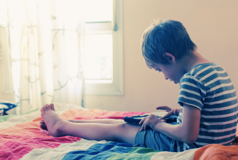 boy reading, sitting on bed