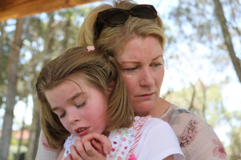 mother holds young daughter - they both look sad