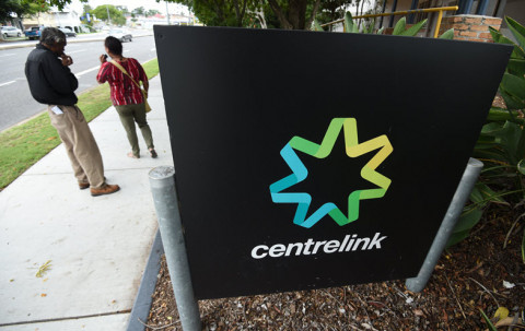 two people smoking near a Centrelink sign