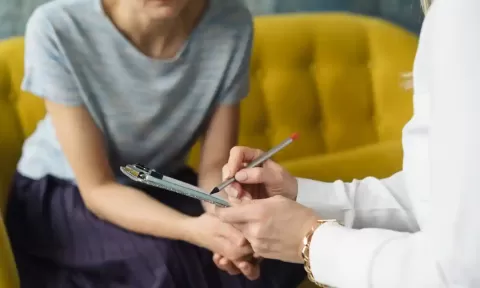 image of hands taking note in front of a woman sitting