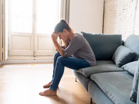 woman sitting on couch feeling troubled