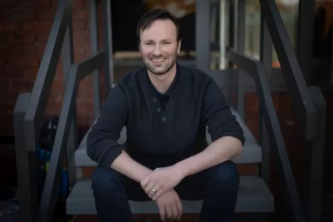 Chris Varney sitting on steps facing the camera