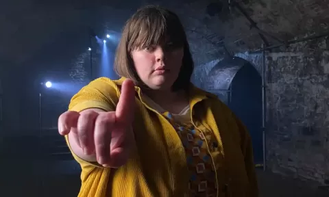 woman facing camera hold up her index finger ... in a stone cellar