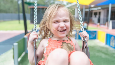 girl smiling and swinging