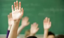 students hands up in front of school chalkboard