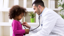 doctor? in lab. coat with stethoscope to young girl's chest
