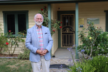 E/Prof Bruce Tonge smiling at camera outside a cottage front door