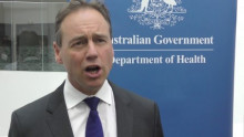 Minister Greg Hunt in front of Commonwealth Health Department logo